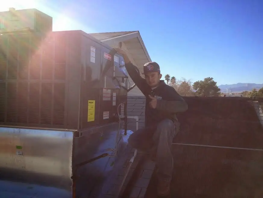 HVAC technician performing AC Tune-Up on a rooftop unit in Alexandria